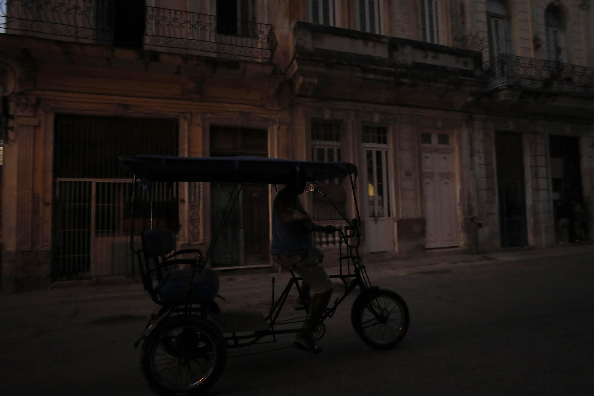 Fotografía de archivo de un 'bicitaxi' al transitar por una calle en penumbra, durante uno de los diarios apagones eléctricos, en La Habana (Cuba). EFE/Yander Zamora
