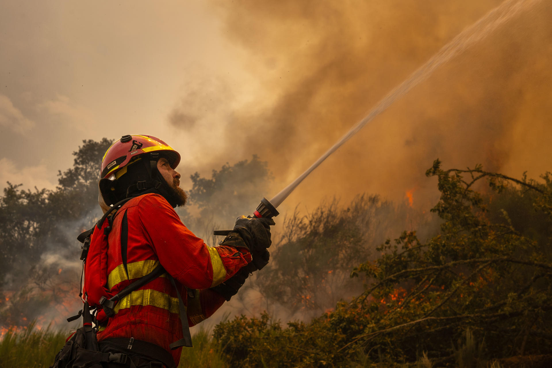 Un efectivo de la Unidad Militar de Emergencias (UME) combate el fuego en la localidad de A Espasa, durante el incendio forestal que permanece activo en Chandrexa de Queixa (Ourense), este martes. EFE/Brais Lorenzo
