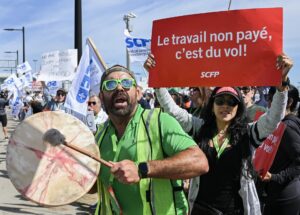 Trabajadores de Air Canada portan una pancarta en la que se puede leer "El trabajo no pagado es un robo" durante una concentración este lunes en el Aeropuerto Internacional Trudeau de Montreal. EFE/GRAHAM HUGHES