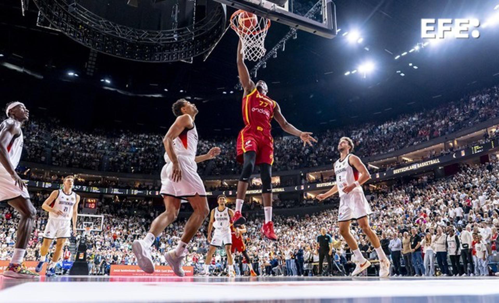 El pivot de España Yankuba Sima (c) efectúa un mate ante varios rivales de Alemania durante el partido amistoso preparatorio para el Eurobasket 2025 celebrado en el Lanxess Arena de Colonia. EFE/FEB/Alberto Nevado