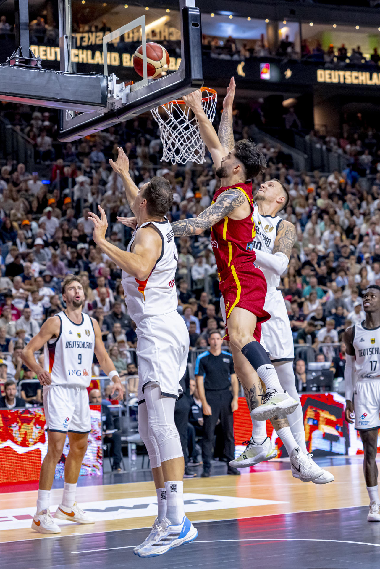 El alero de España Santi Yusta (2d) lucha por el rebote con el pívot de Alemania Daniel Theis (d) durante el partido amistoso preparatorio para el Eurobasket 2025 celebrado este sábado en el Lanxess Arena de Colonia. EFE/FEB/Alberto Nevado