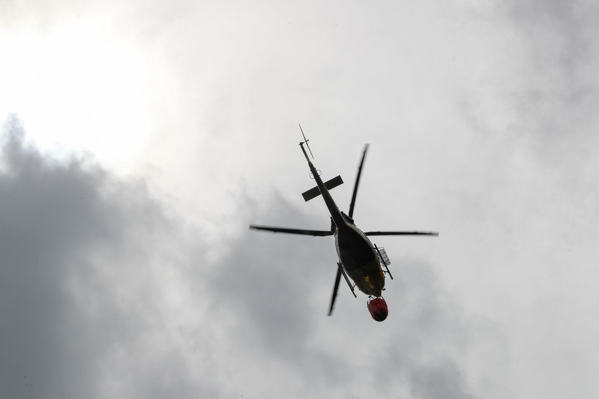 Un helicóptero realiza labores de enfriamiento del terreno, este miércoles en una zona montañosa de Augasmestas, en Quiroga (Lugo). EFE/Eliseo Trigo