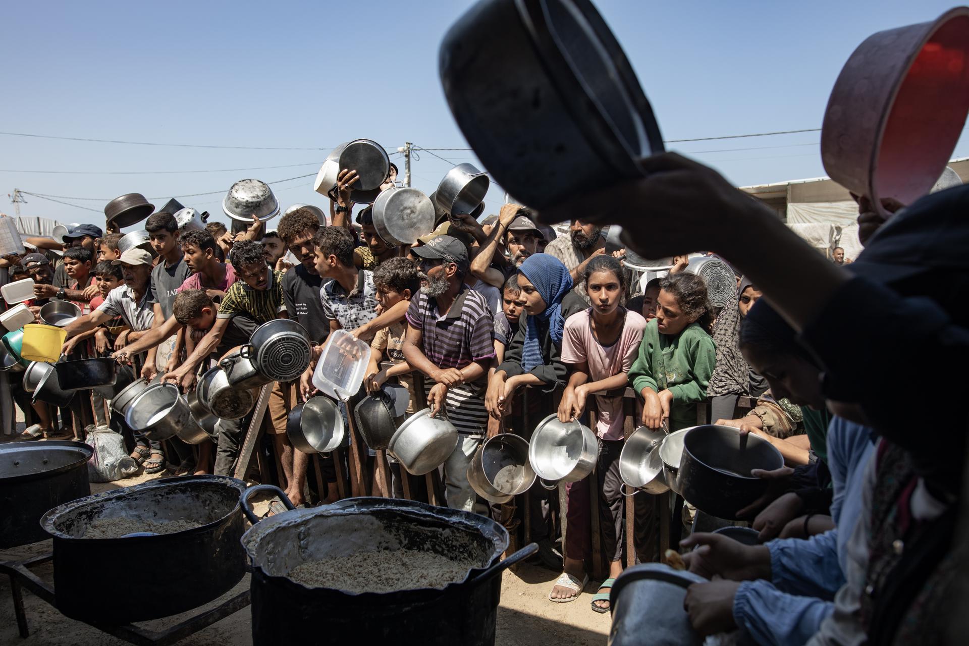 Los palestinos hacen cola para recibir una comida de una cocina que proporciona alimentos gratuitos para las personas desplazadas en Khan Yunis, en la Franja de Gaza sur, el 23 de agosto de 2025. EFE/EPA/HAITHAM IMAD
