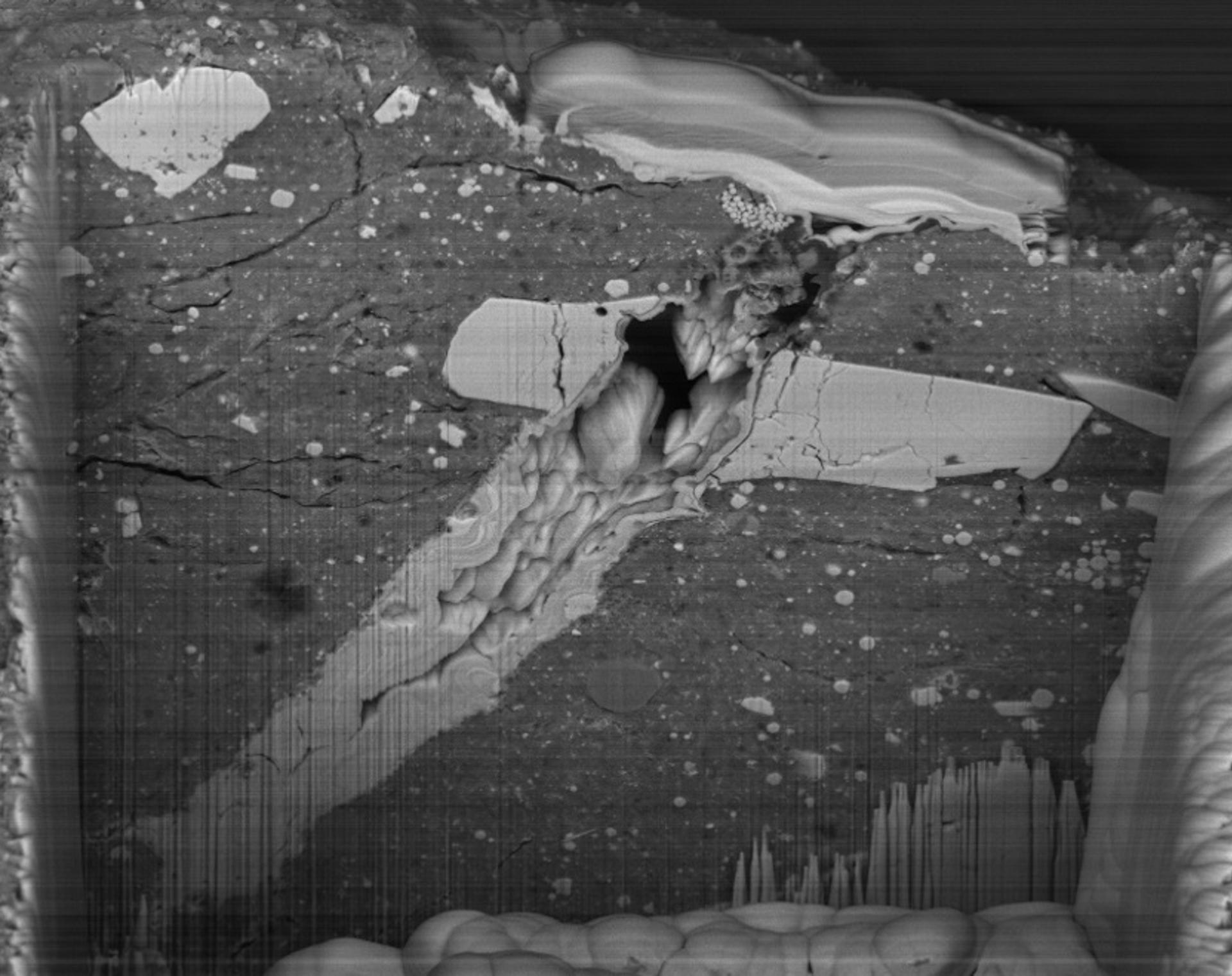 Una imagen de microscopio electrónico de barrido del cráter de impacto de micrometeorito en una partícula de material del asteroide Bennu. EFE/Crédito: NASA