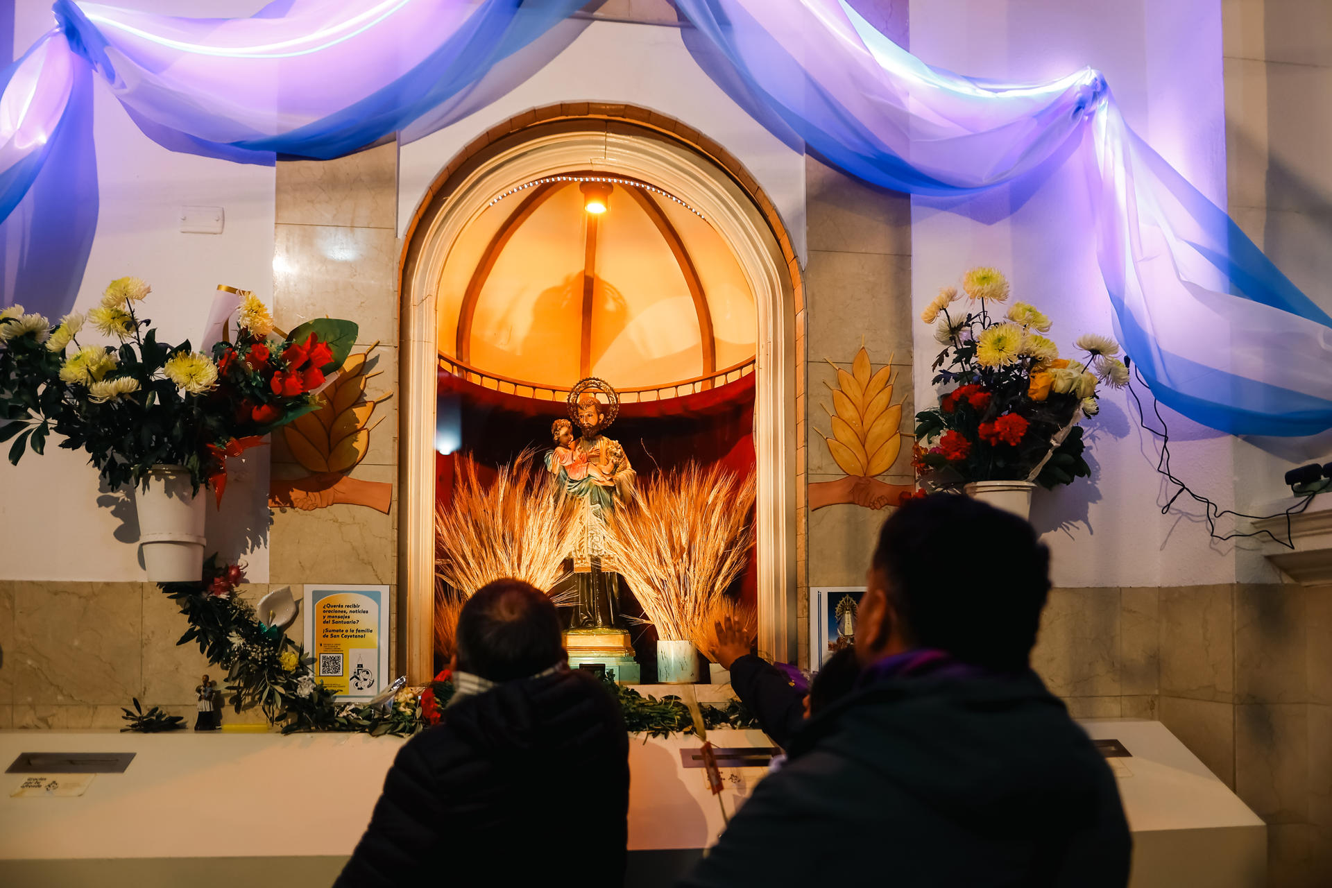 Personas observan una imagen religiosa durante la conmemoración del Día de San Cayetano este jueves, en el barrio Liniers en Buenos Aires (Argentina). EFE/ Juan Ignacio Roncoroni
