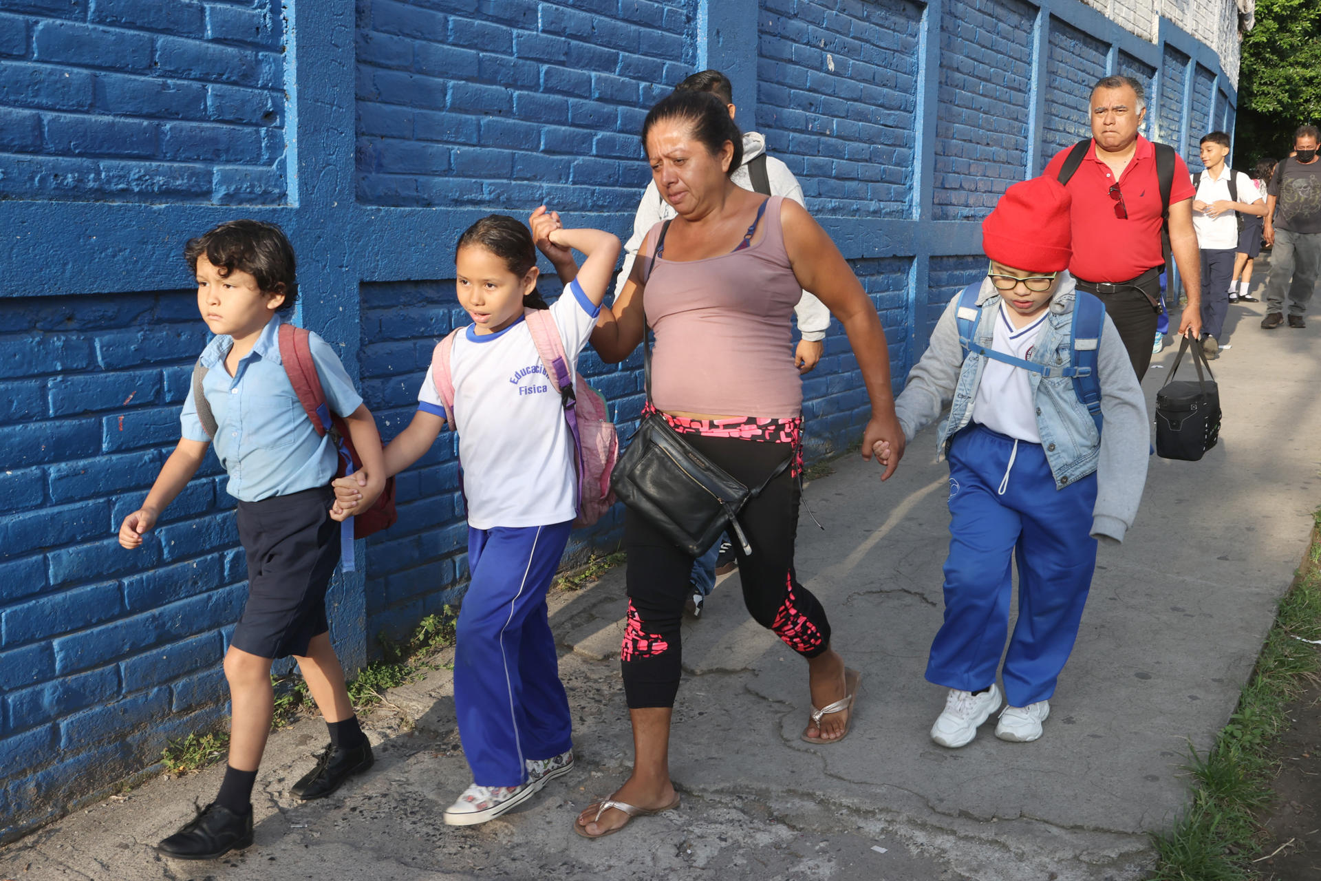 Una madre de familia lleva a sus hijos al Complejo Educativo República Oriental del Uruguay este miércoles, en San Salvador (El Salvador). EFE/ Javier Aparicio
