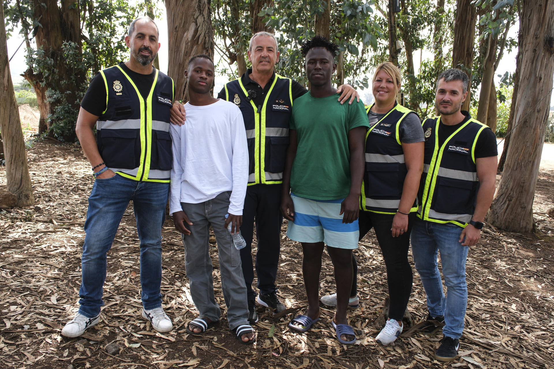 Los policías nacionales Víctor (3i), Manuel (i), Sandra (2d) y Daniel (d), quienes participaron del rescate de los migrantes cuyo cayuco volcó a finales del mes de mayo en el puerto de La Restinga en El Hierro, visitan a dos de los supervivientes, Habib (2i) y Amara (3d), en el exterior del Centro de Primeras Llegadas de Las Raíces en Tenerife, donde se encuentran actualmente. EFE/Alberto Valdés