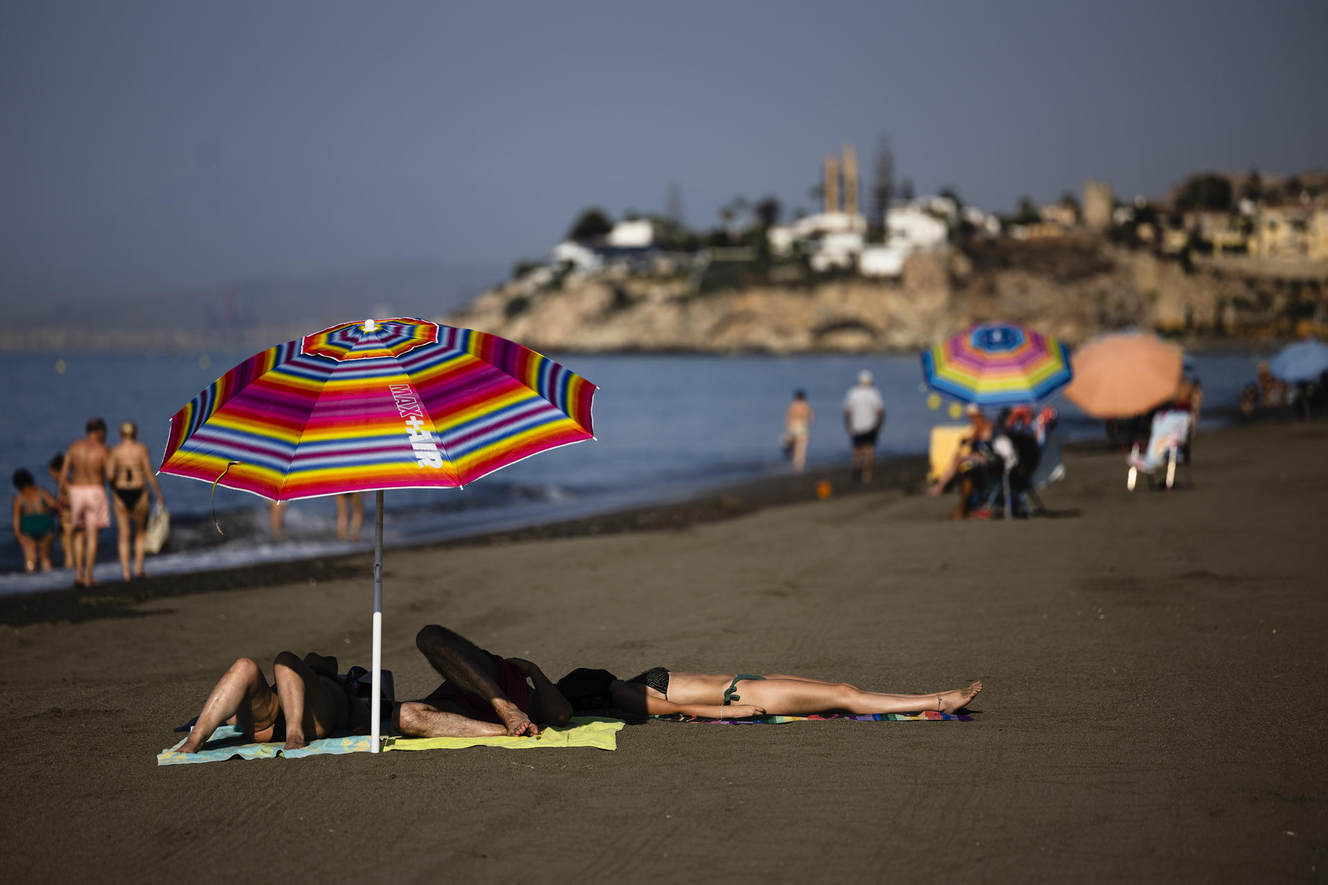 Varias personas se resguardan del sol baja una sombrilla en la playa del Rincón de la Victoria (Málaga), este miércoles. EFE/Jorge Zapata