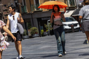 Varias personas se protegen del sol en el centro de Toledo, este jueves. EFE/Ismael Herrero