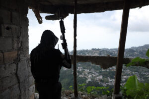 Fotografía de archivo en la que se ve a un integrante de la Policía Nacional de Haití (PNH) se refugia en una casa, tras el ataque de una pandilla armada en Kenscoff (Haití). EFE/ Patrice Noel