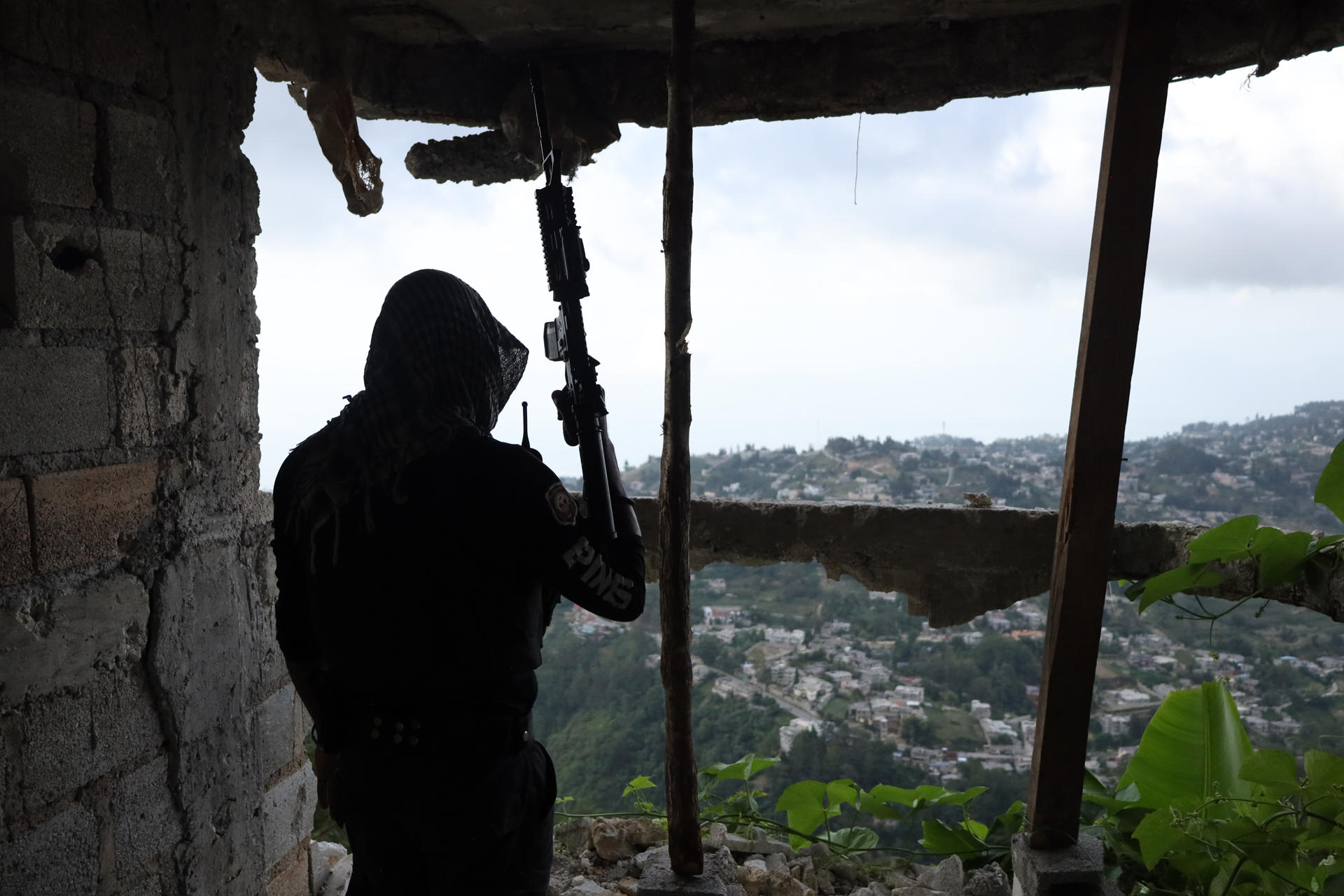 Fotografía de archivo en la que se ve a un integrante de la Policía Nacional de Haití (PNH) se refugia en una casa, tras el ataque de una pandilla armada en Kenscoff (Haití). EFE/ Patrice Noel