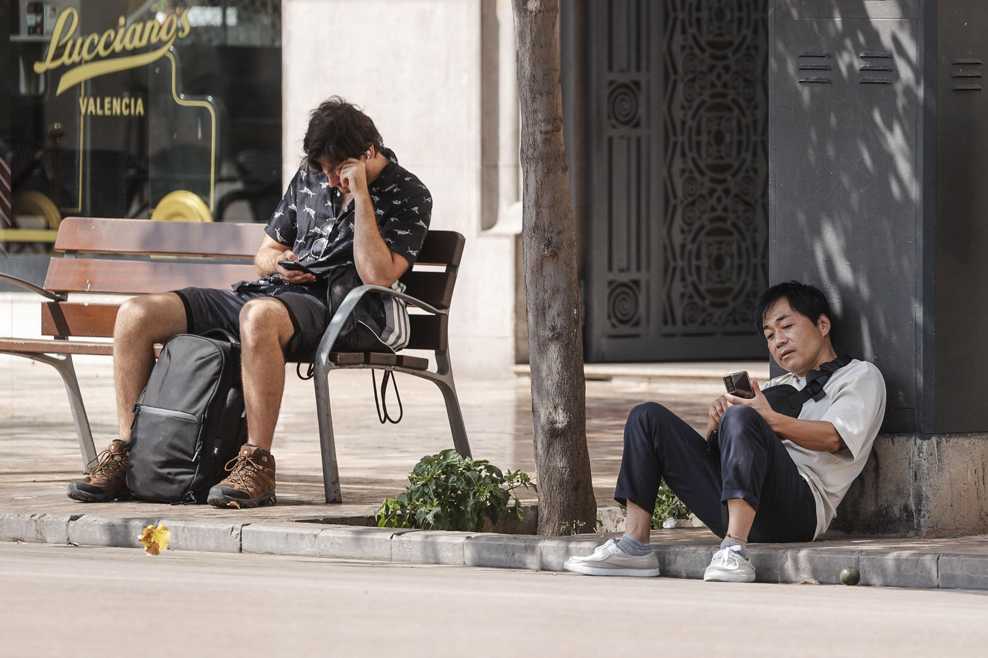 Dos hombres se toman un respiro a la sombra, este lunes 18 de agosto, en la plaza del Ayuntamiento de València. La Agencia Estatal de Meteorología mantiene el aviso de nivel rojo por altas temperaturas en el sur de Alicante, donde las máximas rozarán los 42 grados, mientras que en la mayor parte de Valencia será naranja y amarillo en Castellón, tras una noche nuevamente sofocante en muchos puntos de la Comunitat con valores por encima de los 30 grados durante la madrugada. EFE/Manuel Bruque
