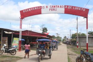 Personas se movilizan en una calle que muestra un letrero fronterizo este miércoles, en la población de Santa Rosa, una isla en medio del río Amazonas bajo soberanía peruana, situada frente a la ciudad colombiana de Leticia, en la triple frontera amazónica con Brasil. EFE/ Stringer