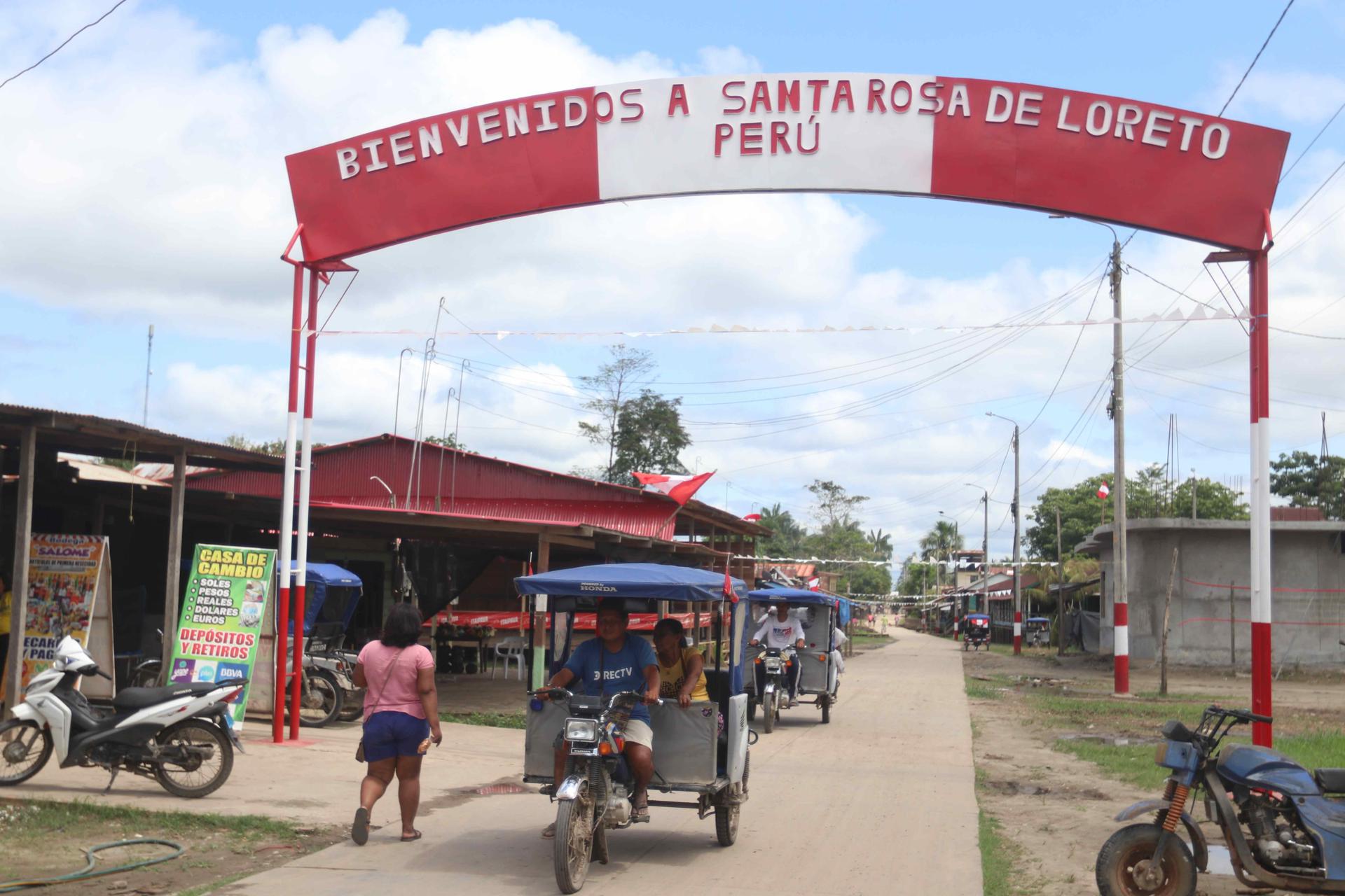 Personas se movilizan en una calle que muestra un letrero fronterizo este miércoles, en la población de Santa Rosa, una isla en medio del río Amazonas bajo soberanía peruana, situada frente a la ciudad colombiana de Leticia, en la triple frontera amazónica con Brasil. EFE/ Stringer