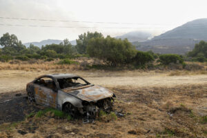 Un coche calcinado por el fuego en Tarifa, Medios del Servicio de Extinción de Incendios Forestales de Andalucía (Infoca) prosiguen este miércoles la lucha contra el incendio forestal declarado de Tarifa (Cádiz) el martes en la zona de la Peña, en el que más de un centenar de efectivos han trabajado esta noche y que provocó el desalojo de instalaciones turísticas. EFE/A.Carrasco Ragel.