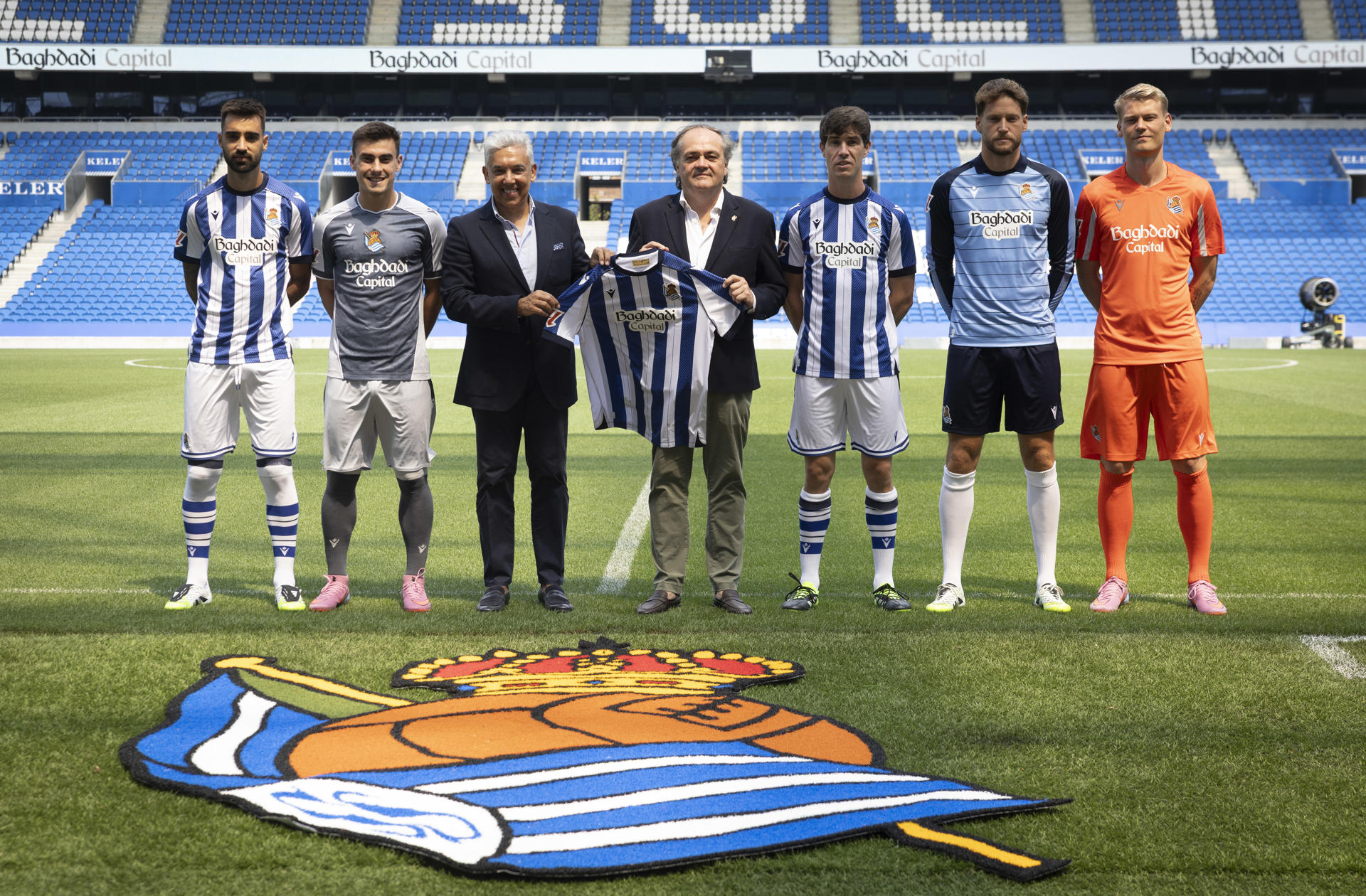 El presidente de la Real Sociedad, Jokin Aperribay (c), el presidente y fundador de Baghdadi Capital, Baihas Baghdadi (3i), y los jugadores Brais Méndez (i), Ander Barrenetxea (2i), Aritz Elustondo (3d), Álex Remiro (2d) y Orri Óskarsson (d), posan este jueves durante la presentación de este compañía financiera como nuevo patrocinador del club blanquiazul. EFE/Javier Etxezarreta

