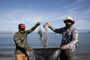 Dos personas muestran desechos en una playa este jueves, en Las Salinas de Baní (República Dominicana). EFE/Orlando Barría