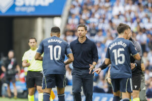 El delantero francés del Real Madrid, Kylian Mbappé, y el entrenador Xavi Alonso durante el partido de la jornada 4 de La Liga EA Sports este sábado en el estadio Municipal de Anoeta en San Senastián.- EFE/ Juan Herrero