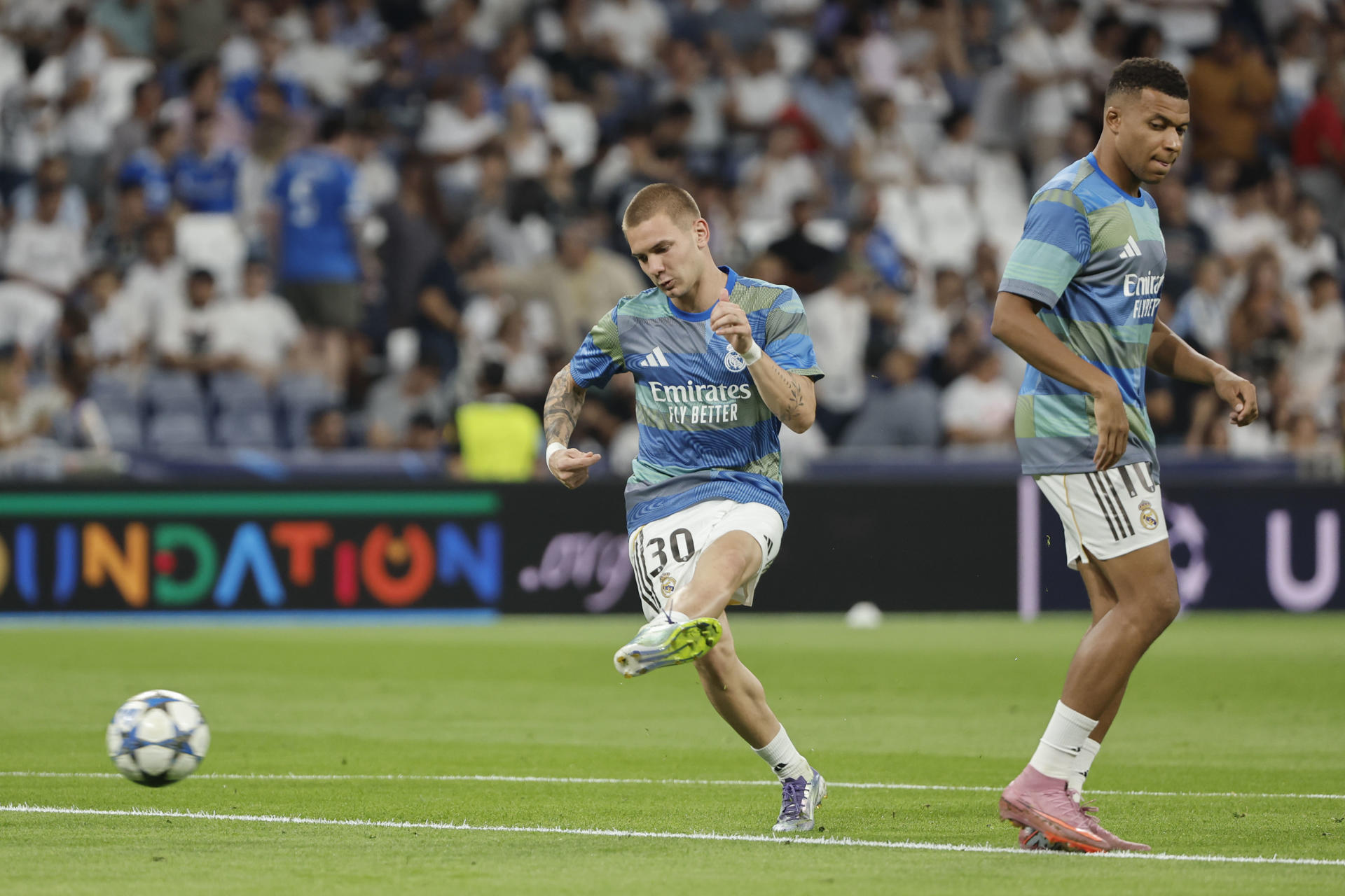Los delanteros del Real Madrid Kylian Mbappé (d) y Franco Mastantuono (i) calientan antes del partido de la primera jornada de la Liga de Campeones entre Real Madrid y Olympique de Marsella, este martes en el estadio Santiago Bernabéu de Madrid. EFE/ Sergio Pérez
