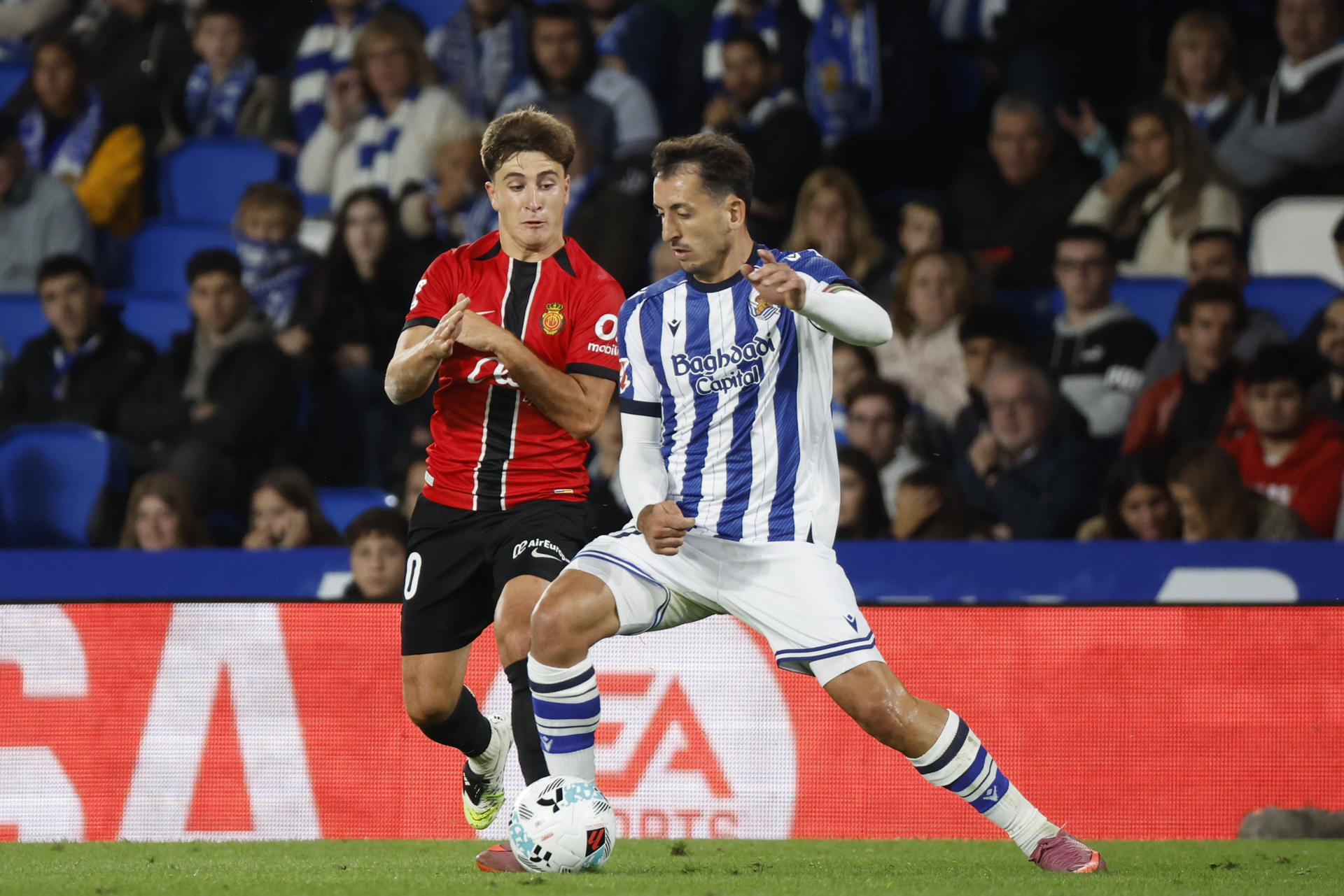 El delantero de la Real Sociedad, Mikel Oyarzabal (d), disputa el balón ante el centrocampista del Mallorca, Pablo Torre, durante el encuentro correspondiente a la sexta jornada de LaLiga de fútbol que Real Sociedad y RCD Mallorca disputan en el Reale Arena, en San Sebastián. EFE/Juan Herrero

