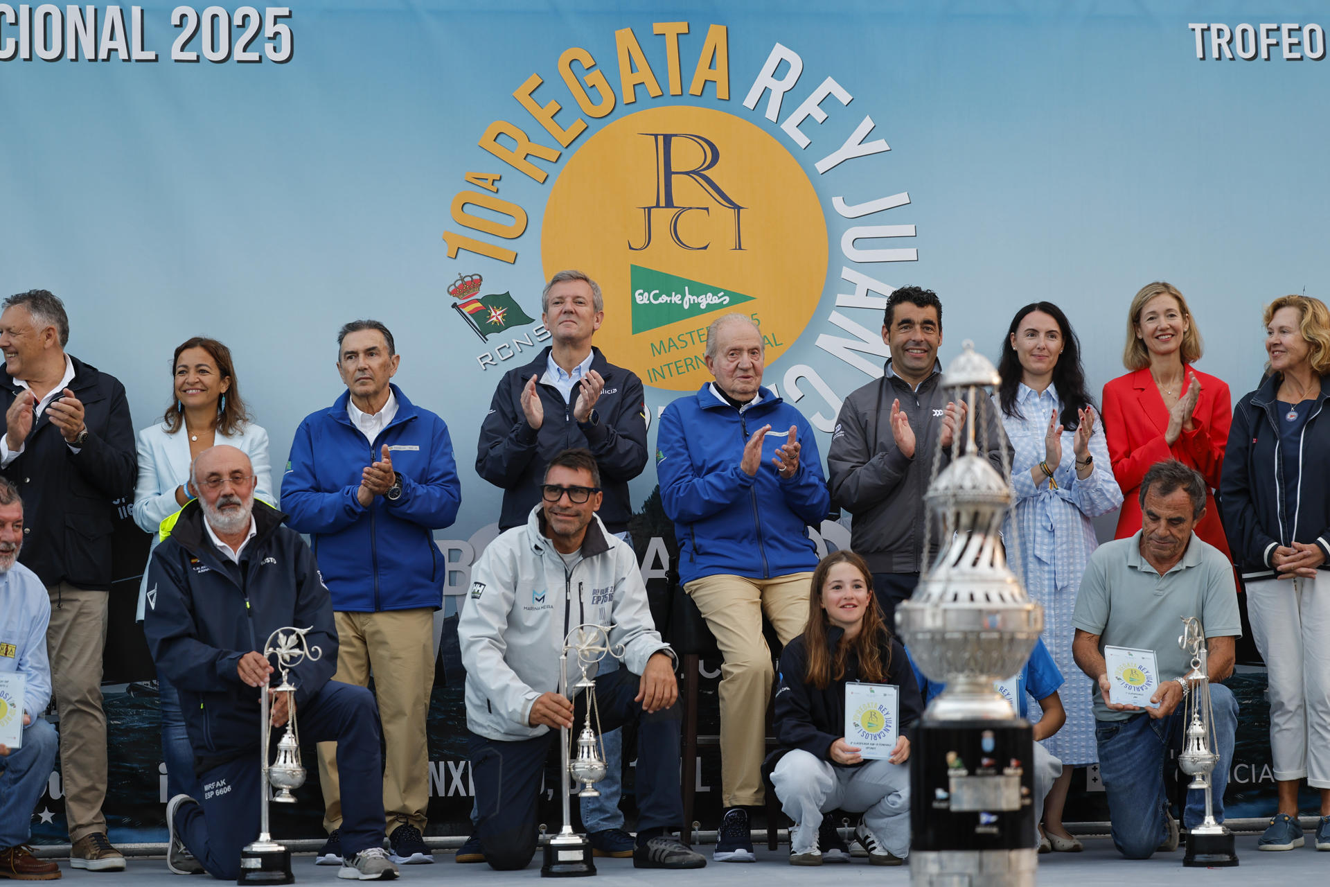 El rey emérito acompañado del presidente de la Xunta de Galicia Alfonso Rueda, posa junto a los ganadores durante la entrega de premios de la regata en la que participan deportistas de once países, este domingo en el Real Club Náutico de Sanxenxo.EFE/ Lavandeira Jr

