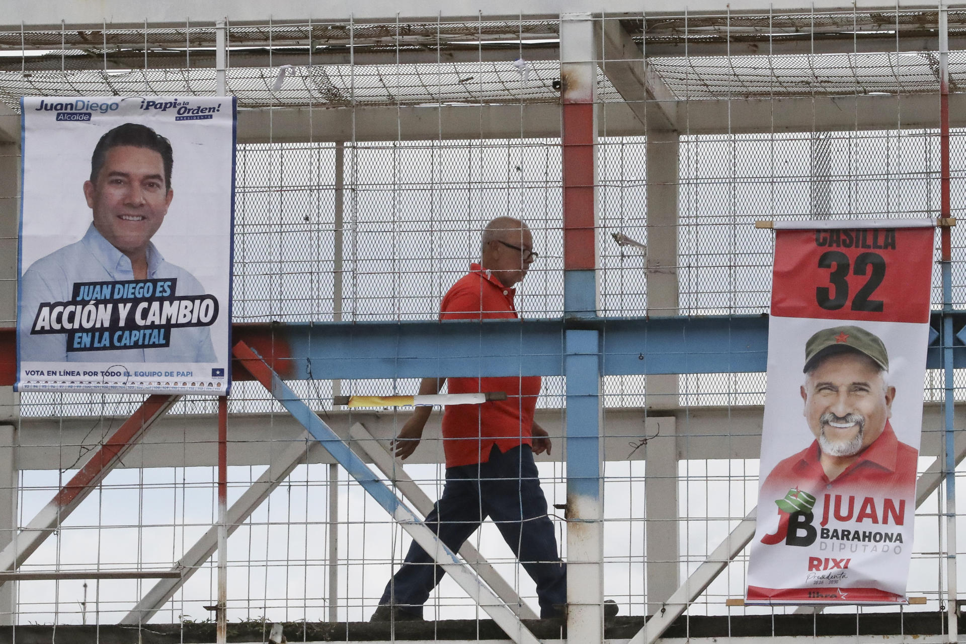 Una persona camina junto a carteles alusivos a la campaña electoral este lunes, en Tegucigalpa (Honduras). EFE/ STR