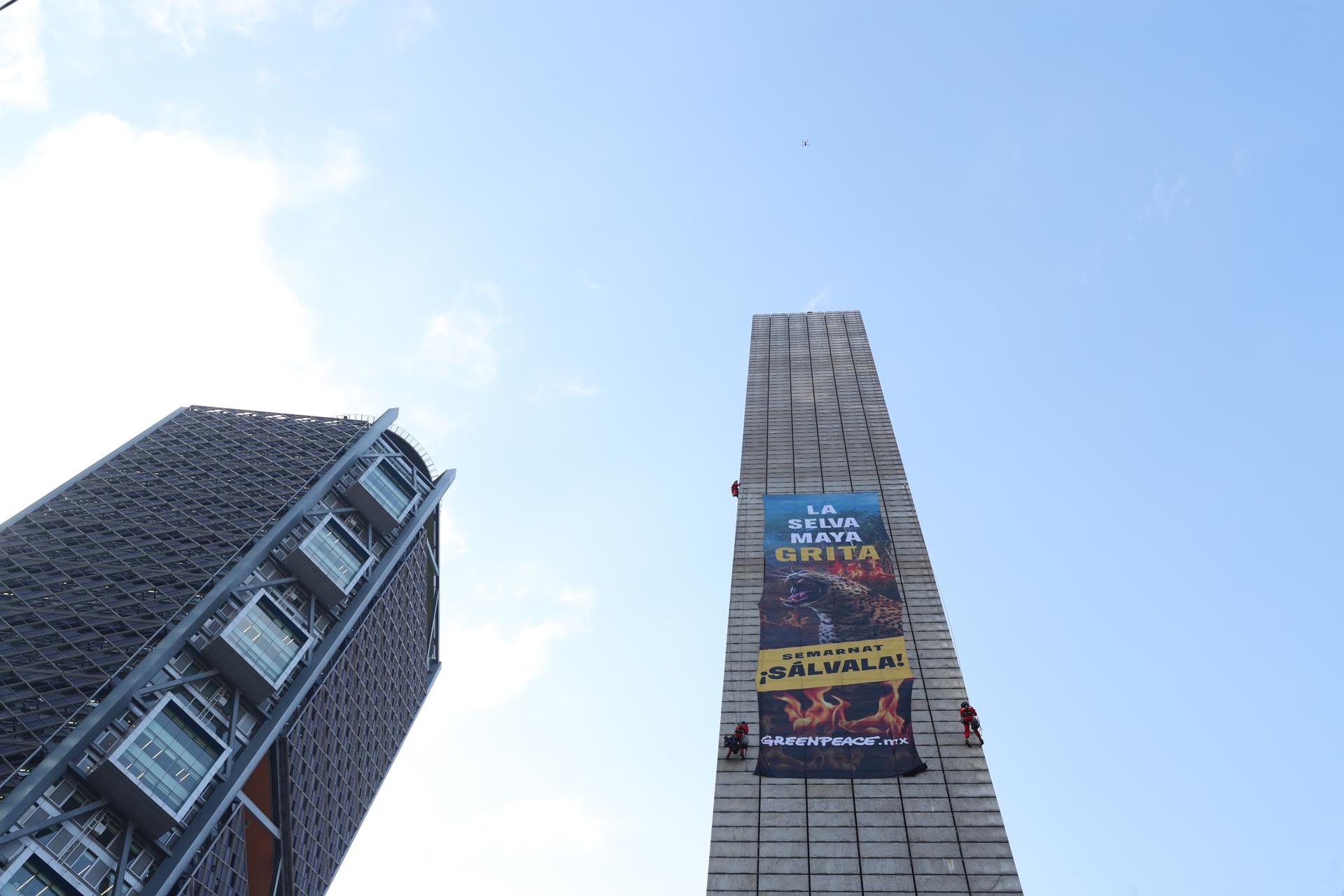 Integrantes de la organización ambientalista Greenpeace protestan colgando un cartel en la Estela de Luz este martes, en Ciudad de México (México). EFE/ Mario Guzmán