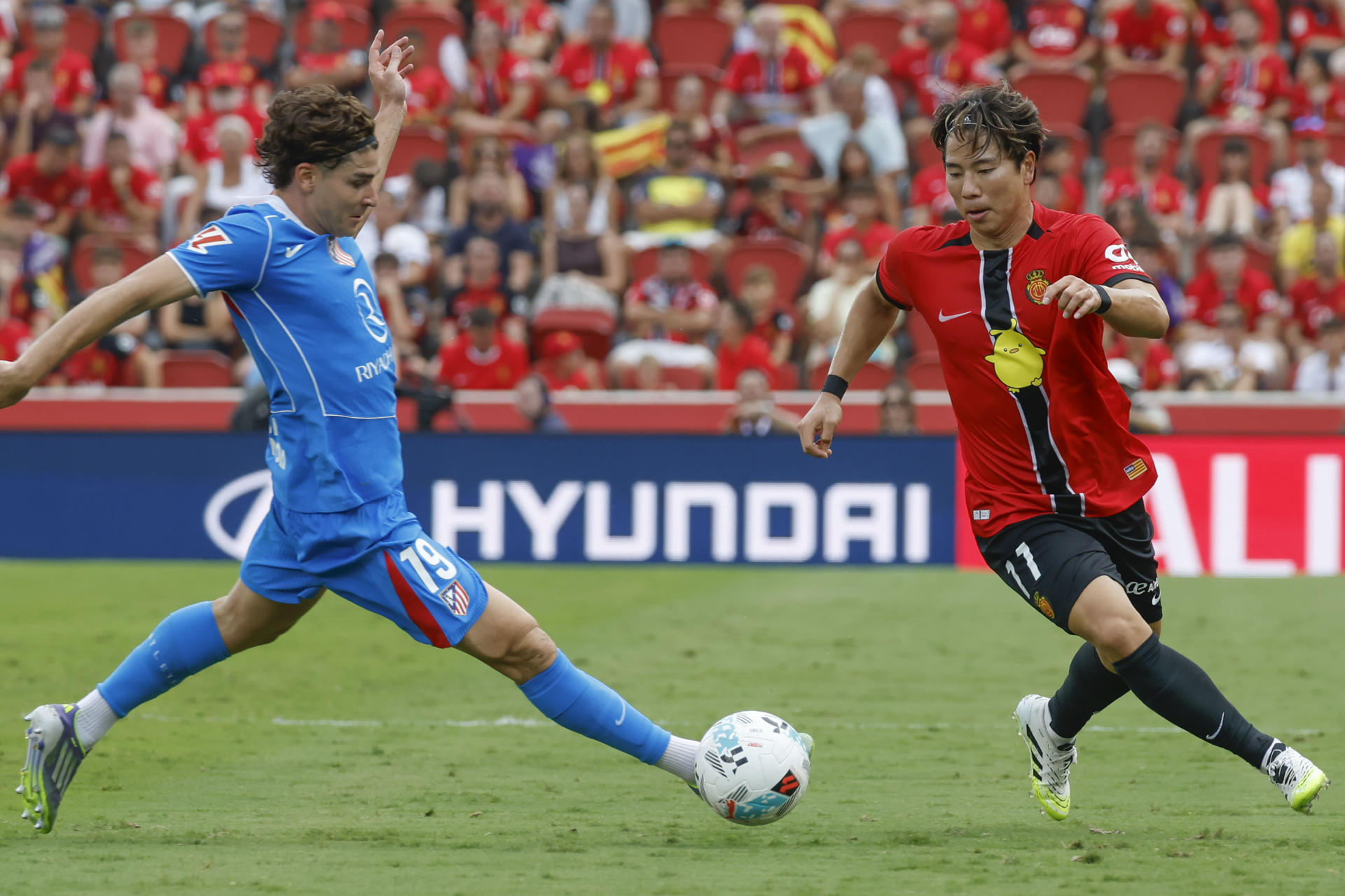 El delantero japonés del Mallorca Takuma Asano pelea un balón ante el delantero argentino del Atlético de Madrid Julián Álvarez (i) este domingo, durante el partido de la jornada 5 de LaLiga EA SPorts, entre el Real Mallorca y el Atlético de Madrid, que se disputa en el estadio de Son Moix de Palma de Mallorca. EFE/ CATI CLADERA