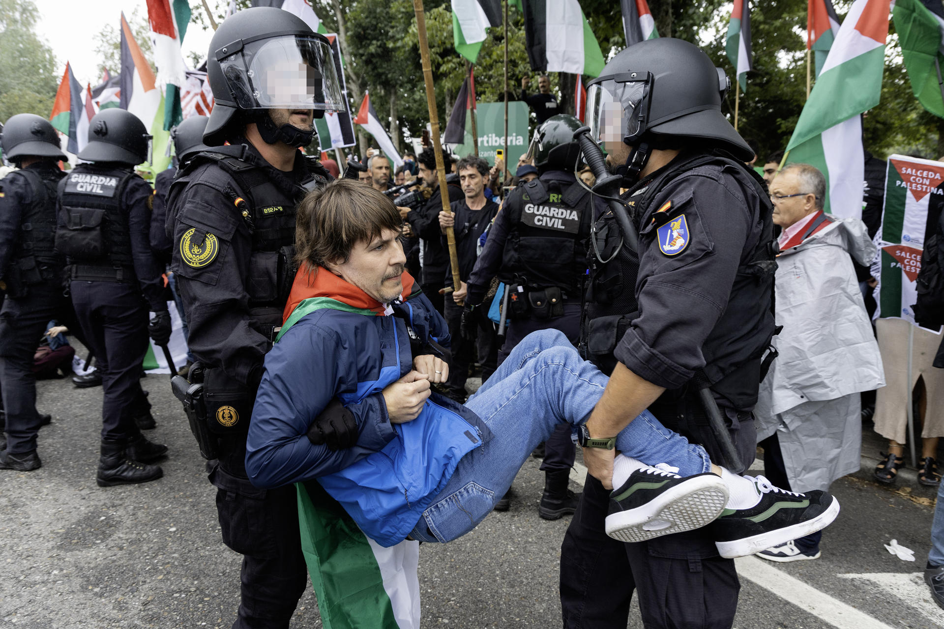 Agentes de la Guardia Civil y la Policía Nacional intervienen debido a la manifestación de numerosas personas que se concentran en el Alto de San Cosme para protestar por la presencia del equipo Israel-Premier Tech en la Vuelta a España, este martes durante la decimosexta etapa de la Vuelta a España entre las localidades pontevedresas de Poio y Mos. Las cargas policiales y la decisión de la organización de neutralizar la carrera a 8 kilómetros de la línea de meta marcaron esta etapa. EFE/ Salvador Sas
