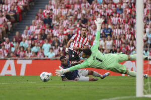 El delantero del Athletic Álex Berenguer (c) trata de batir al guardameta del Arsenal David Raya (d) durante el primer partido de la fase de la Liga de Campeones entre el Athletic Club de Bilbao y el Arsenal, este martes en el estadio de San Mamés en Bilbao. EFE/ Luis Tejido