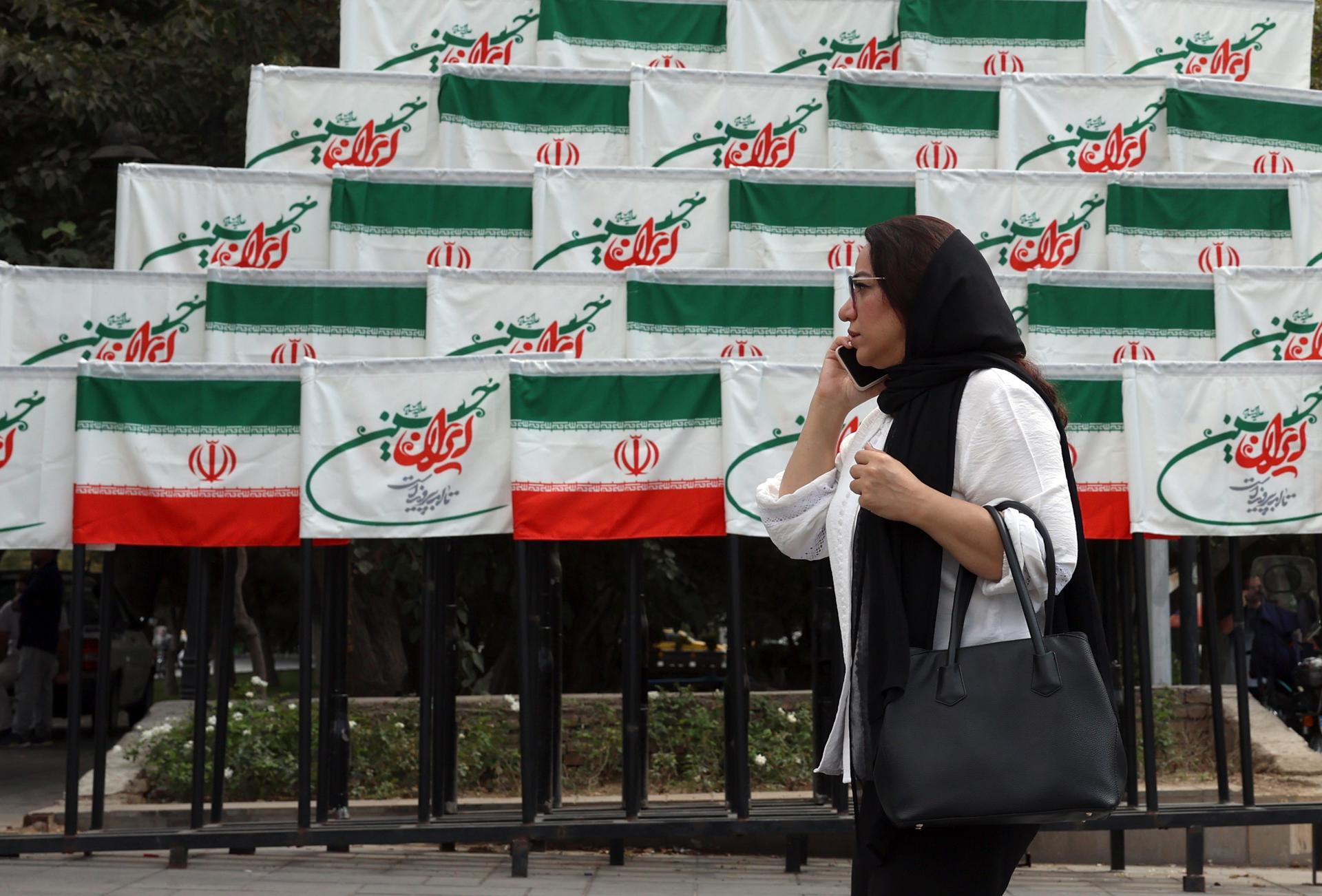 TEHRAN, 27/09/2025.- Una mujer pasea por delante de decenas de banderas iraníes en el centro de Teheran. (Francia, Alemania, Reino Unido, Teherán) EFE/EPA/ABEDIN TAHERKENAREH