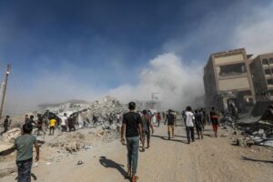 Los palestinos pasan junto a los escombros mientras el humo se eleva del edificio residencial al-Roya tras un ataque aéreo israelí en el oeste de la ciudad de Gaza, Franja de Gaza, 8 de septiembre de 2025. EFE/EPA/MOHAMMED SABER