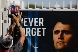 Una persona fue captada este sábado, 20 de septiembre, al colocar una bandera estadounidense en un memorial improvisado en honor del activista político ultraconservador Charlie Kirk, a las afueras de la sede de su fundación, Turning Point USA, en Phoenix (Arizona, EE. UU.). EFE/Caroline Brehman
