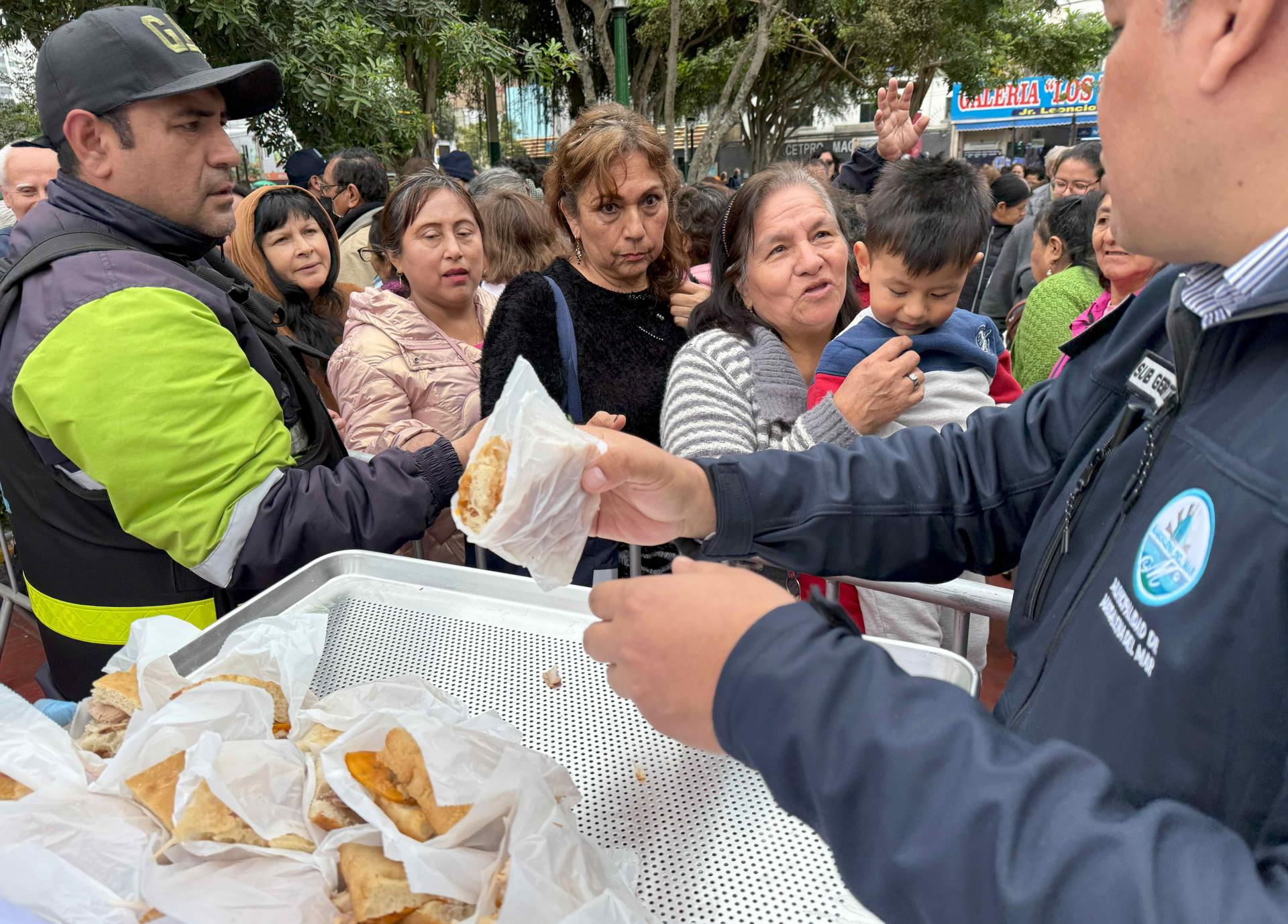 Personas hacen fila para recibir una porción de pan con chicharrón este miércoles, en el distrito de Magdalena del Mar, en Lima (Perú).EFE/ Mikhail Huacán
