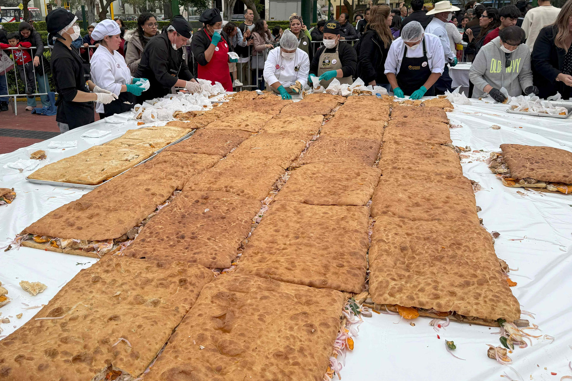 Personas preparan un pan con chicharrón este miércoles, en el distrito de Magdalena del Mar, en Lima (Perú). EFE/ Mikhail Huacán