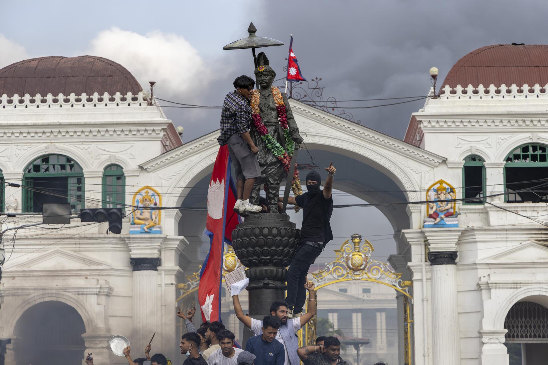 Katmandú (Nepal), 09/09/2025.- Manifestantes instalan la bandera nacional en la estatua del primer rey de Nepal, Prithvi Narayan Shah, durante violentas manifestaciones en Katmandú. EFE/EPA/NARENDRA SHRESTHA