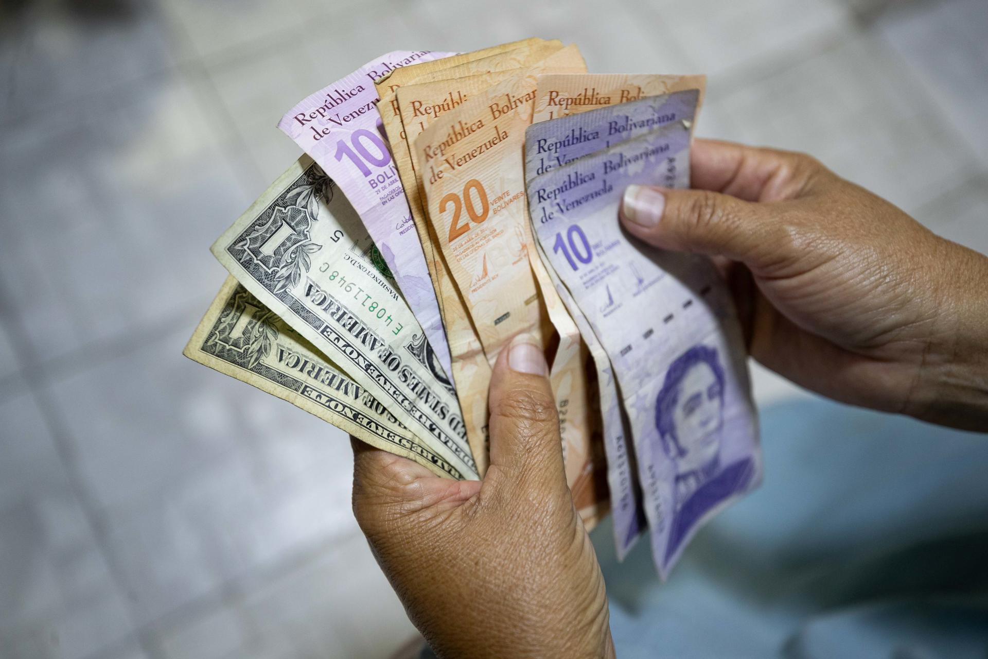 Fotografía de archivo de una persona que muestra billetes de bolívares y dólares en Caracas (Venezuela). EFE/ Ronald Peña R