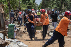 Integrantes del cuerpo de bomberos y protección civil atienden una mujer afectada por una explosión de una fábrica de fuegos artificiales este jueves, en San Francisco (Venezuela). EFE/ Henry Chirinos