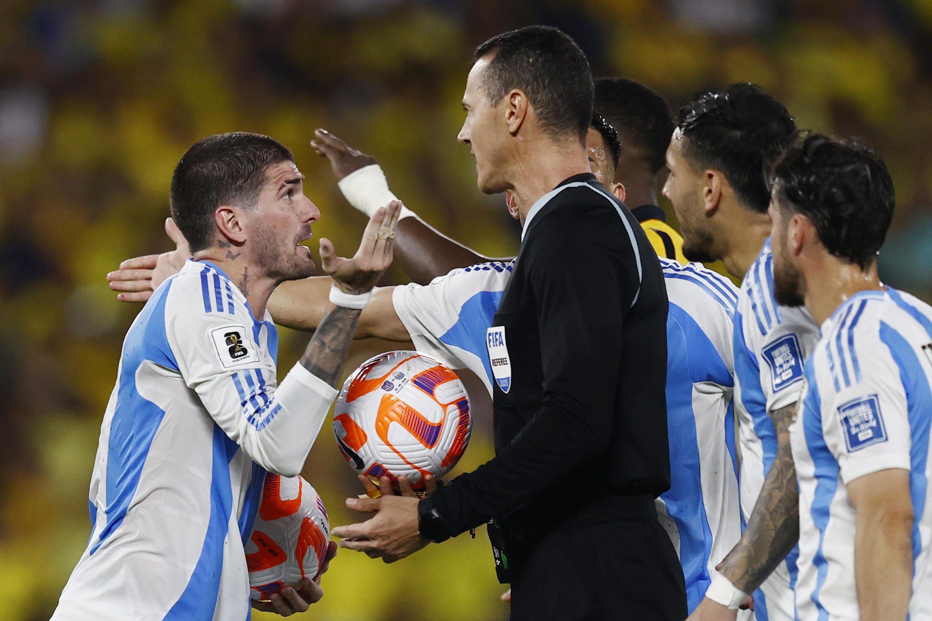 Rodrigo De Paul (i), de Argentina, le reclama al árbitro Wilmar Roldán, de Colombia, por una decisión este martes en el partido ante Ecuador por las eliminatorias sudamerican al Mundial de 2026. EFE/ José Jácome