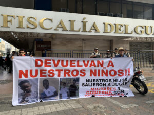 Fotografía del 23 de diciembre de 2024 que muestra a dos personas sosteniendo un cartel en los exteriores de la Fiscalía Provincial del Guayas con el mensaje 'devuelvan a nuestros niños', en alusión a los cuatro menores desaparecidos el 8 de diciembre en Guayaquil (Ecuador). EFE/Cristina Bazán