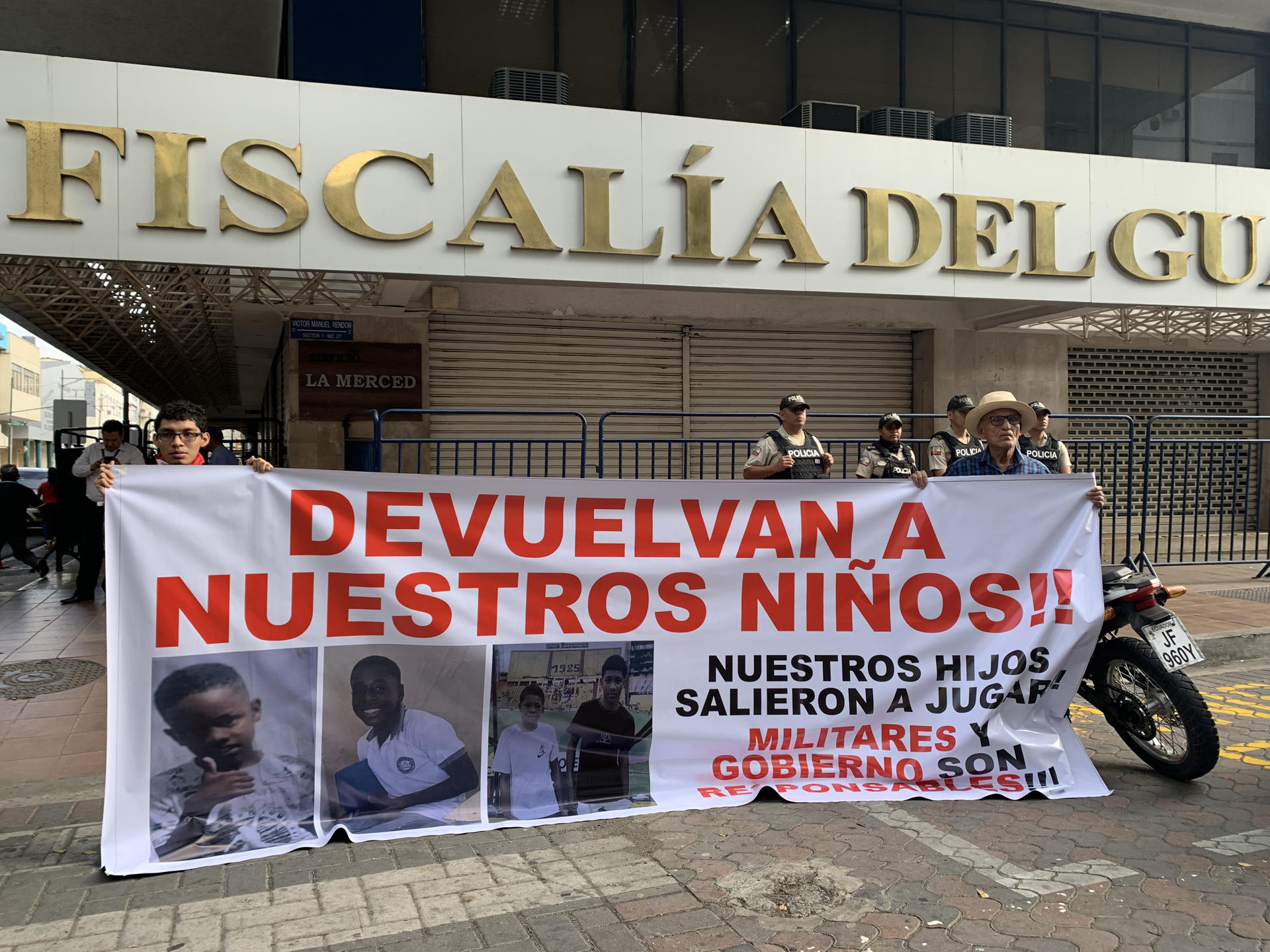 Fotografía del 23 de diciembre de 2024 que muestra a dos personas sosteniendo un cartel en los exteriores de la Fiscalía Provincial del Guayas con el mensaje 'devuelvan a nuestros niños', en alusión a los cuatro menores desaparecidos el 8 de diciembre en Guayaquil (Ecuador). EFE/Cristina Bazán