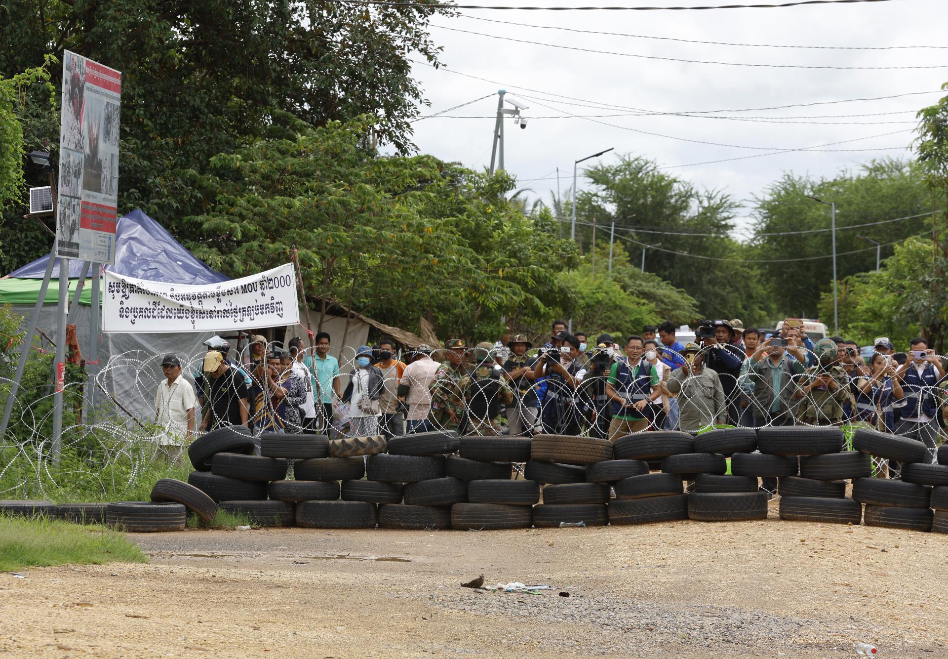 Un grupo de civiles camboyanos tras una barricada colocada por las autoridades tailandesas en un punto de la frontera que ambos países se disputan. 
EFE/EPA/NARONG SANGNAK
