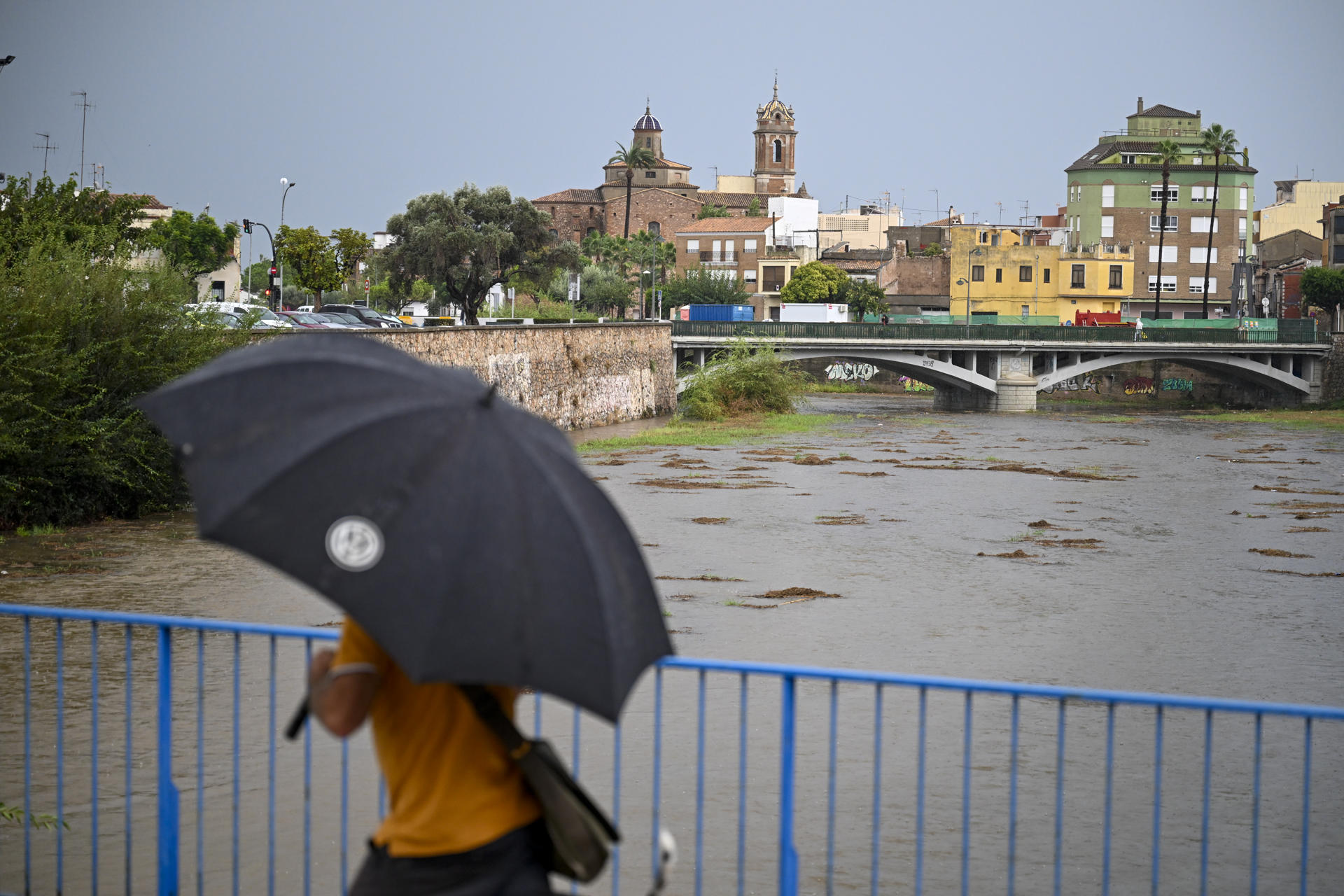 Una persona cruza este lunes un puente sobre el río Ana en Burriana (Castellón). EFE/Andreu Esteban