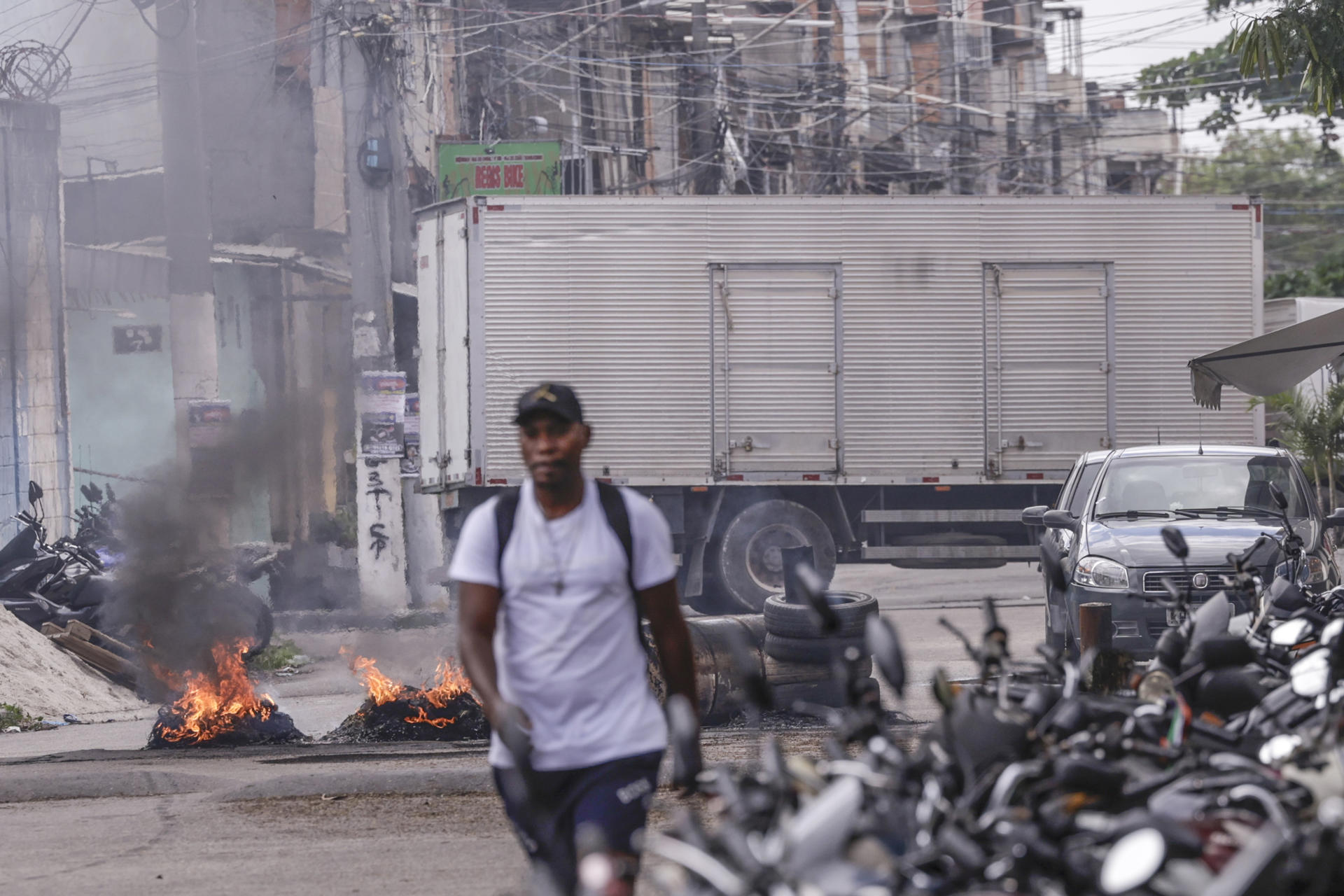 Una persona camina frente a barricadas en llamas durante un operativo policial este viernes, en Río de Janeiro (Brasil). EFE/ André Coelho