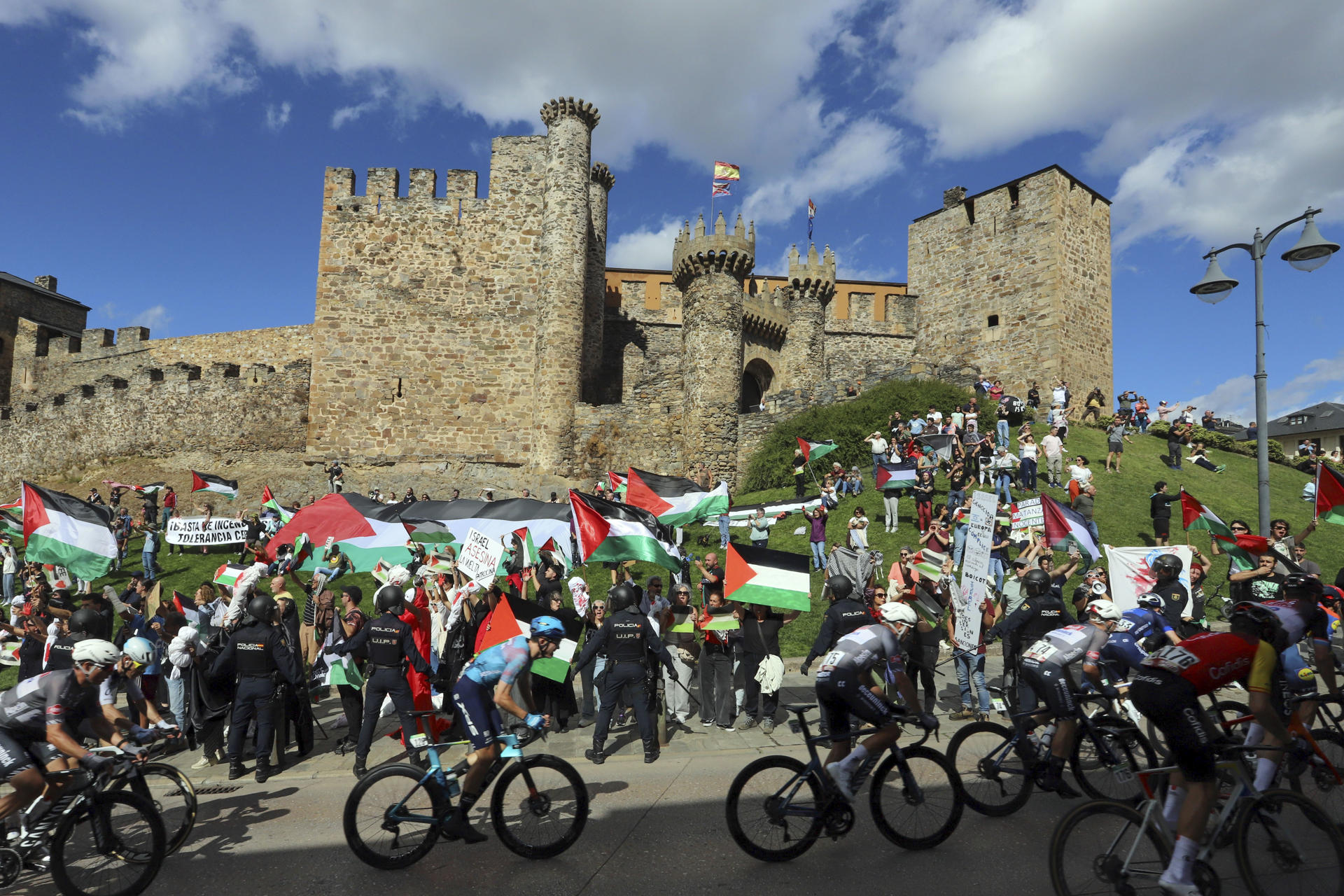 Decenas de personas protestan contra Israel al paso del pelotón por el Castillo de los Templarios en Ponferrada (León), durante la etapa 17 de la Vuelta Ciclista a España, disputada entre O Barco de Valdeorras (Ourense) y Alto de El Morredero (EL Bierzo-León) y con 143,2km de recorrido. EFE/Ana F Barredo