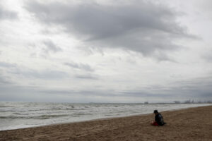 Una persona aguarda en la playa de la Patacona durante este martes en el que la Comunitat Valenciana afronta por segundo día una situación meteorológica adversa, con alerta naranja en el litoral de Alicante y el interior, además del litoral sur de Valencia, en donde las acumulaciones por lluvia serían de hasta 40 l/m2 en una hora, mientras en el litoral norte de Alicante se podrán acumular en doce horas hasta 100 l/m2. EFE/Manuel Bruque