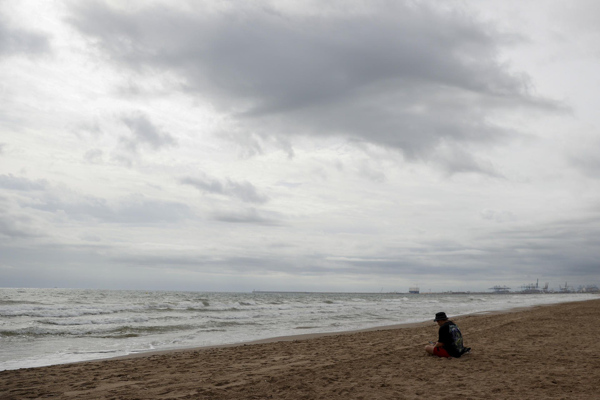 Una persona aguarda en la playa de la Patacona durante este martes en el que la Comunitat Valenciana afronta por segundo día una situación meteorológica adversa, con alerta naranja en el litoral de Alicante y el interior, además del litoral sur de Valencia, en donde las acumulaciones por lluvia serían de hasta 40 l/m2 en una hora, mientras en el litoral norte de Alicante se podrán acumular en doce horas hasta 100 l/m2. EFE/Manuel Bruque