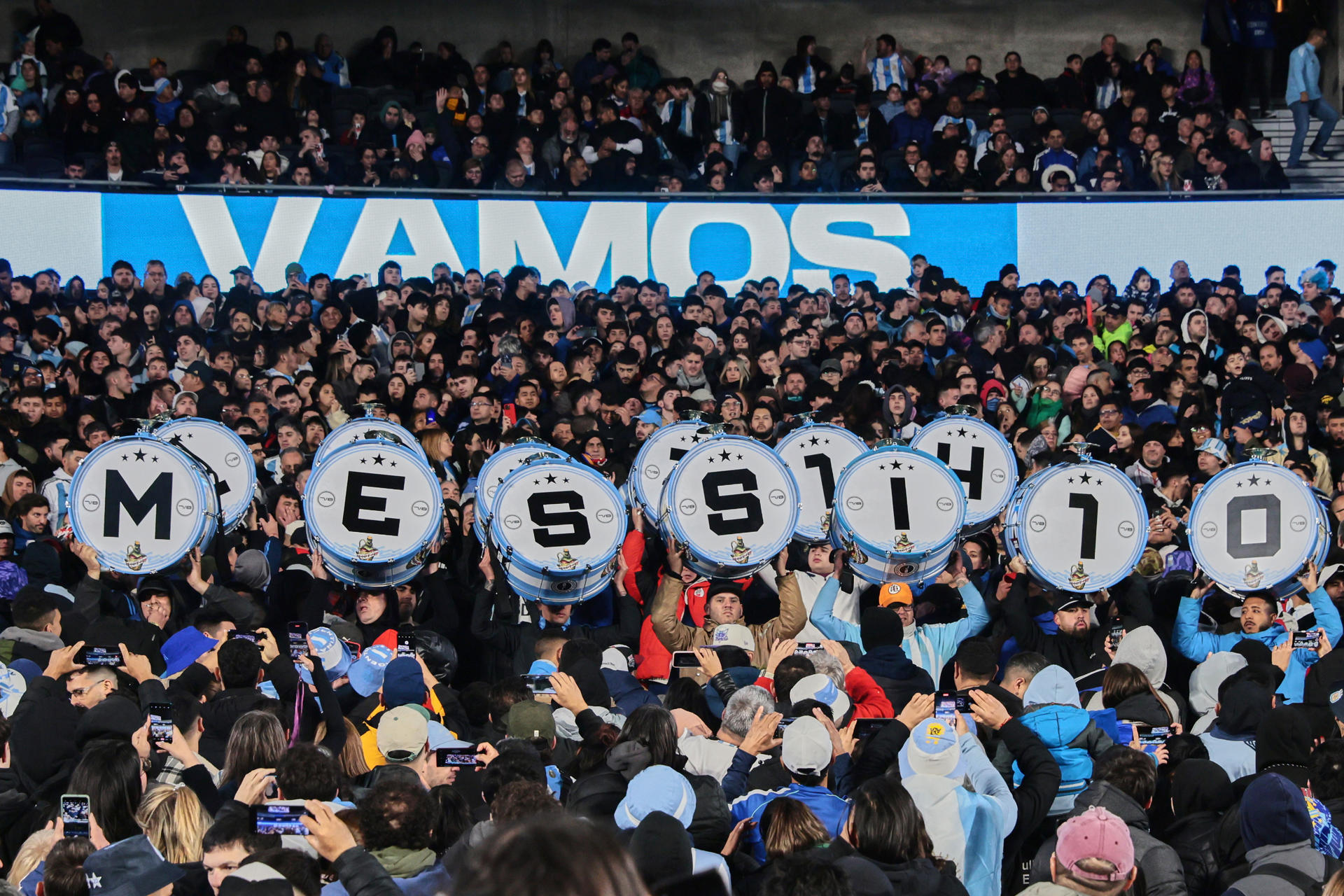 Aficionados argentinos levantan tambores con las iniciales del nombre de Lionel Messi, previo al partido ante Venezuela por las eliminatorias al Mundial 2026 en el estadio Monumental en Buenos Aires. EFE/Adán González