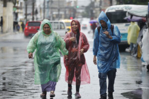 Foto de archivo de tres personas se protegen de la lluvia con capas plásticas en el centro de San Salvador (El Salvador). EFE/Rodrigo Sura