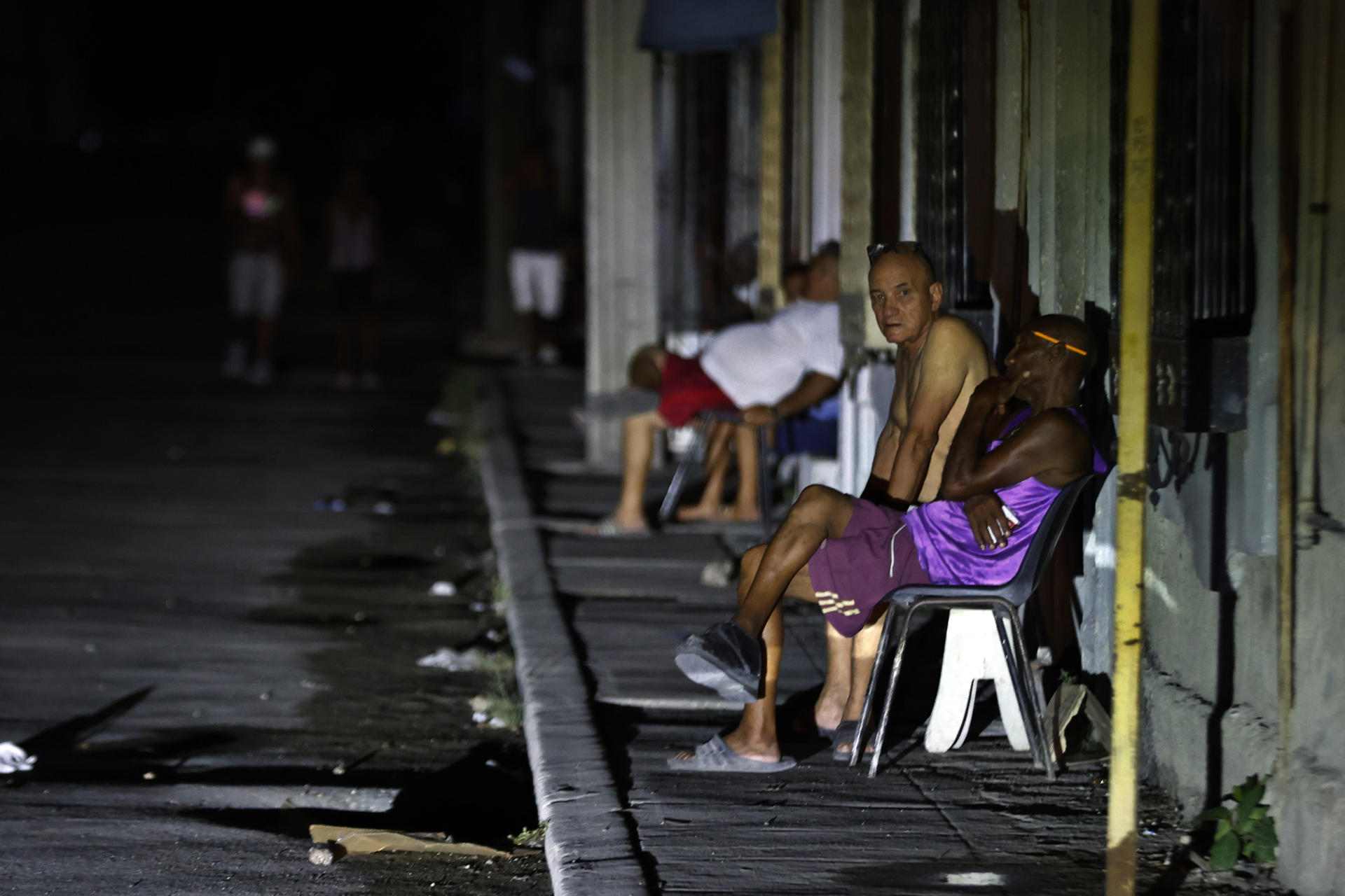 Un grupo de personas fue captado el pasado 21 de agosto al permanecer fuera de sus casas y en medio de una calle sin iluminación, durante uno de los diarios apagones eléctricos, en La Habana (Cuba). EFE/Ernesto Mastrascusa